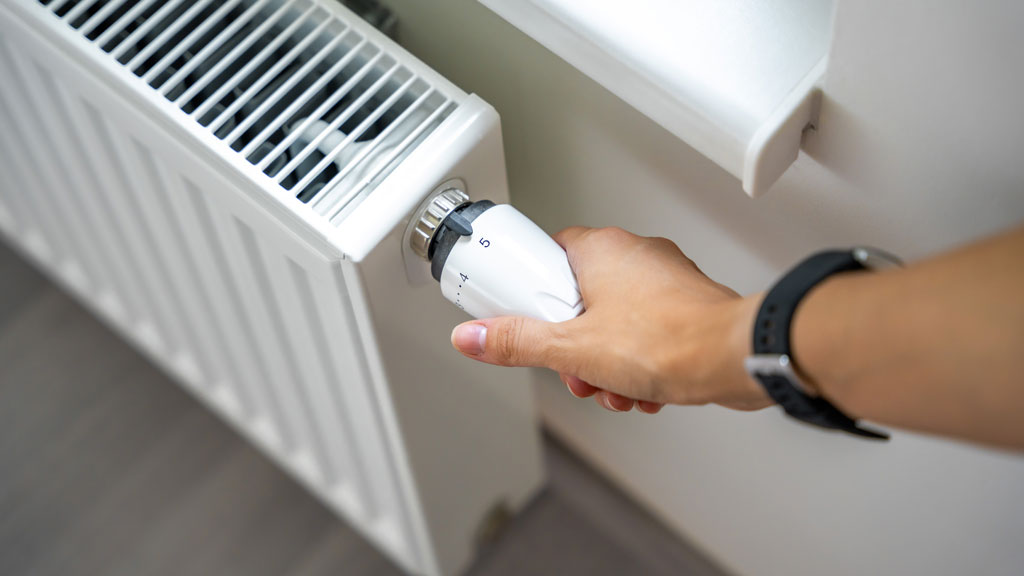 Radiateur en fonte avec vanne thermostatique dans une pièce de maison ancienne (compatibilité PAC)