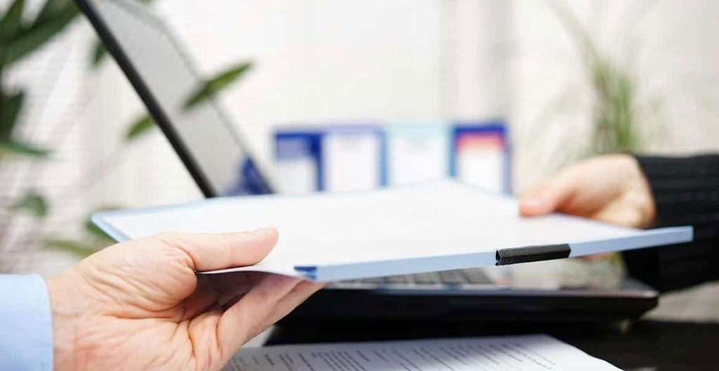 Gros plan sur une main tapant sur le clavier d'un ordinateur portable moderne, écran totalement flouté en arrière-plan, dans un bureau épuré